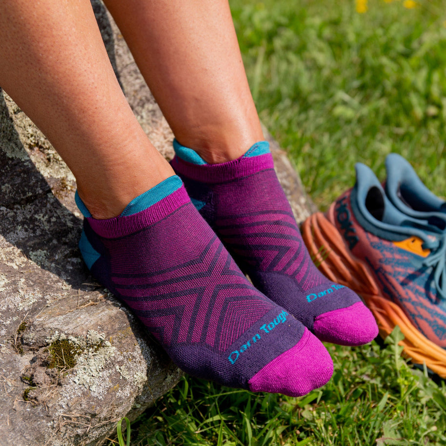 Feet on a rock wearing Darn Tough women's Run No Show Tab socks in Blackberry with running shoes