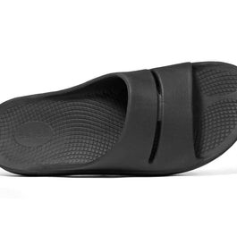 OOahh - Unisex by Oofos in black with OOfoam strap for impact absorption, supportive unisex slides ideal for recovery and casual wear