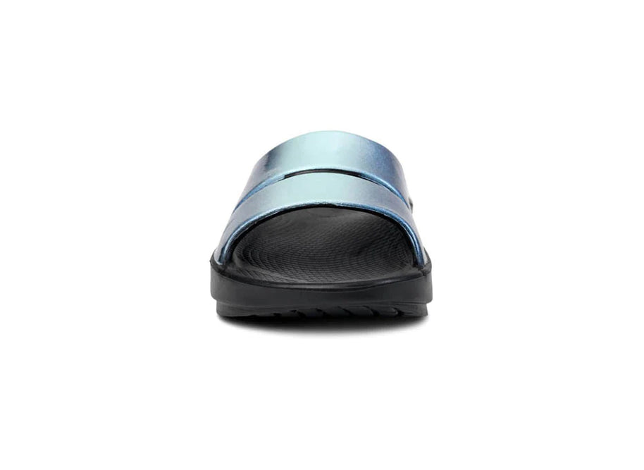 OOahh Luxe - Women by Oofos in metallic blue with OOfoam strap for support and comfort, lightweight slides ideal for casual wear.