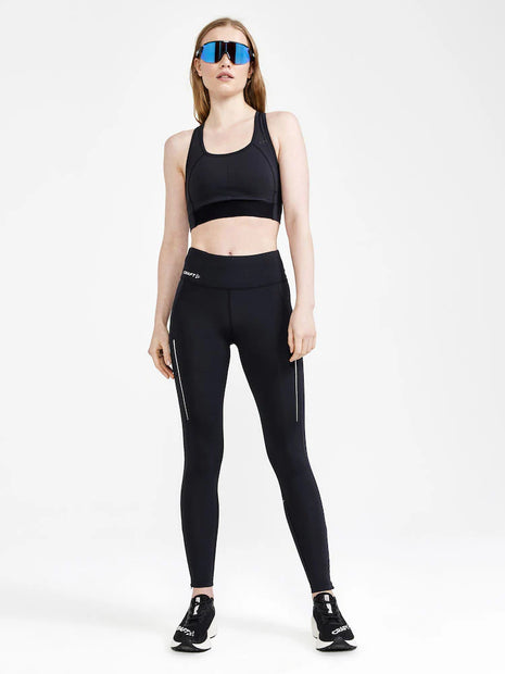 Woman in a black sports bra and sunglasses wearing Craft ADV Essence Run Tights in Black, full-length front