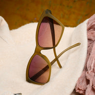 Goodr Sunbaked Sorcery olive sunglasses resting on a cream knit sweater