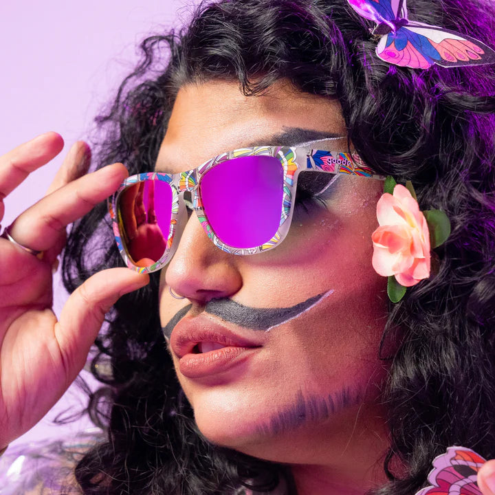Is It Queer In Here Or Is It Just Us?! by Goodr, clear OG frames with purple lenses and butterfly LGBTQ+ flags, unisex glasses for Pride.