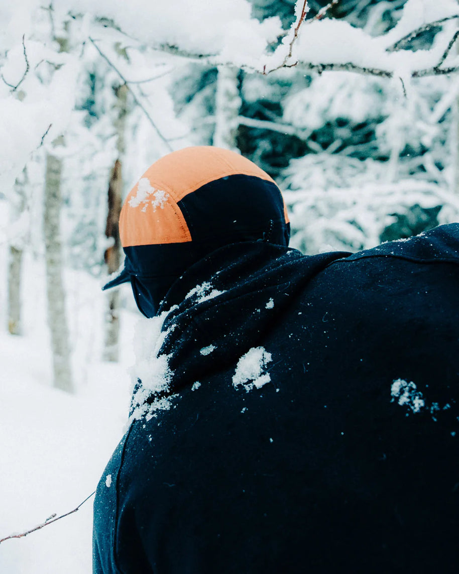 FLTCap WND - Ultra Iconic by Ciele in black and orange with fold-away ear flaps for cold weather running in snowy conditions