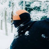 FLTCap WND - Ultra Iconic by Ciele in black and orange with fold-away ear flaps for cold weather running in snowy conditions