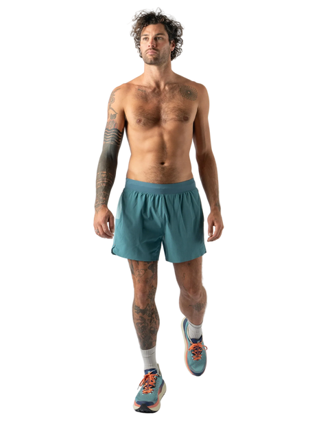 Shirtless runner with curly hair wearing Rabbit FKT 5" men's running shorts in Hydro, full body