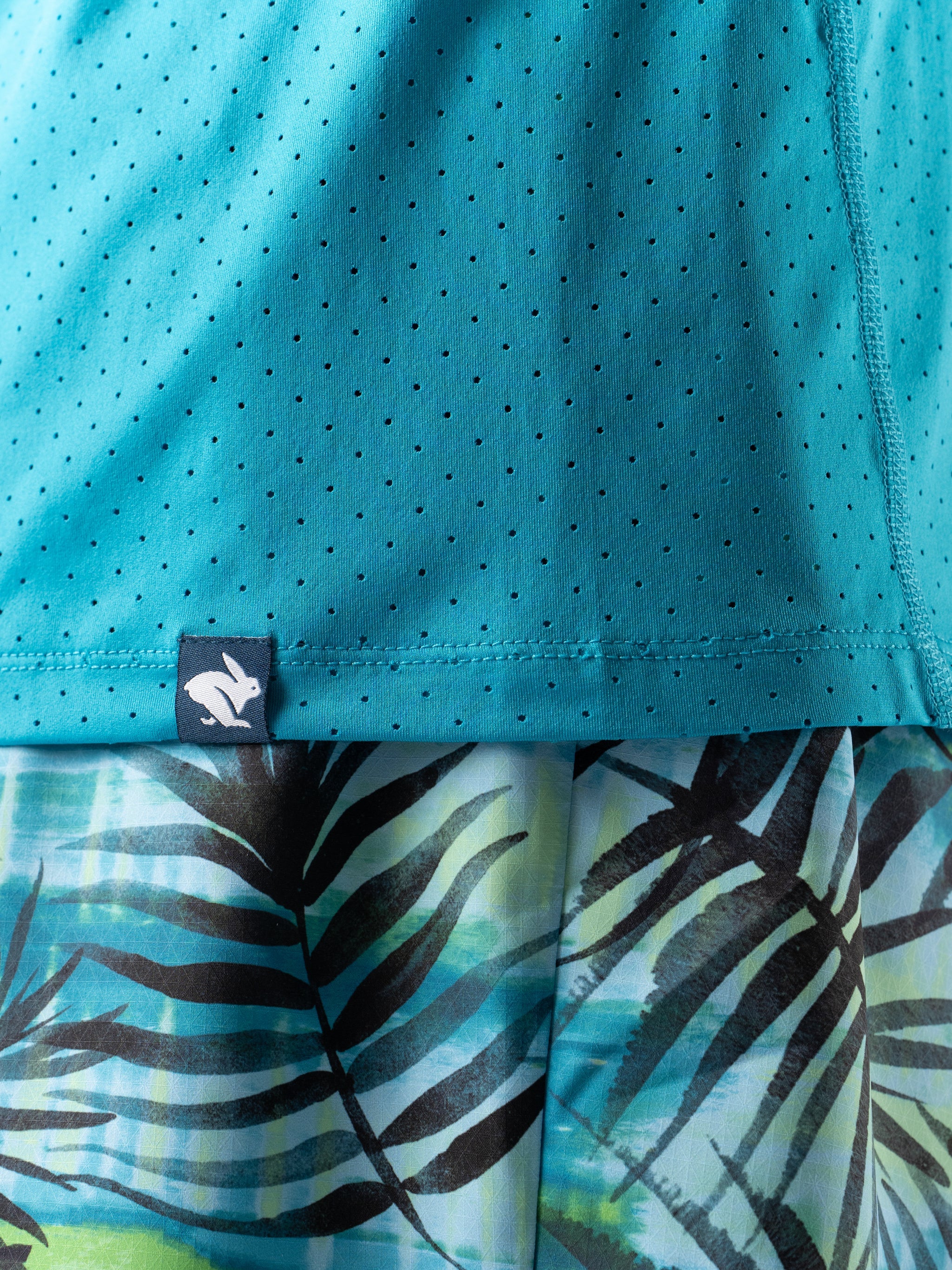 Close-up of turquoise perforated lightweight fabric with Rabbit logo on ICE Perf Tee SS - Men designed for quick-dry comfort and sustainability