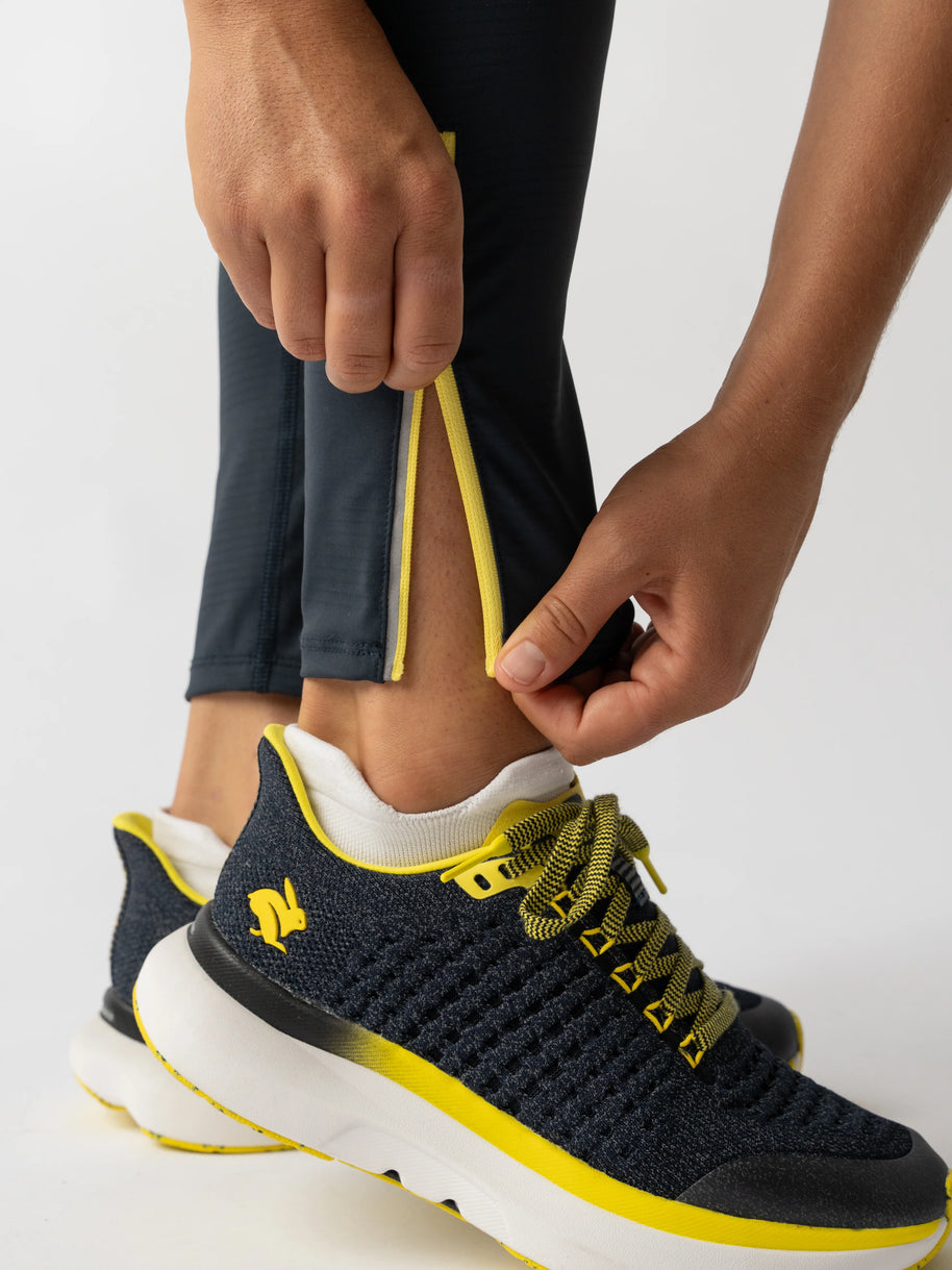 Low Light Speed Tights - Women by Rabbit in black with yellow trim, compressive fit, laser-cut perfs, five pockets, reflective running tights