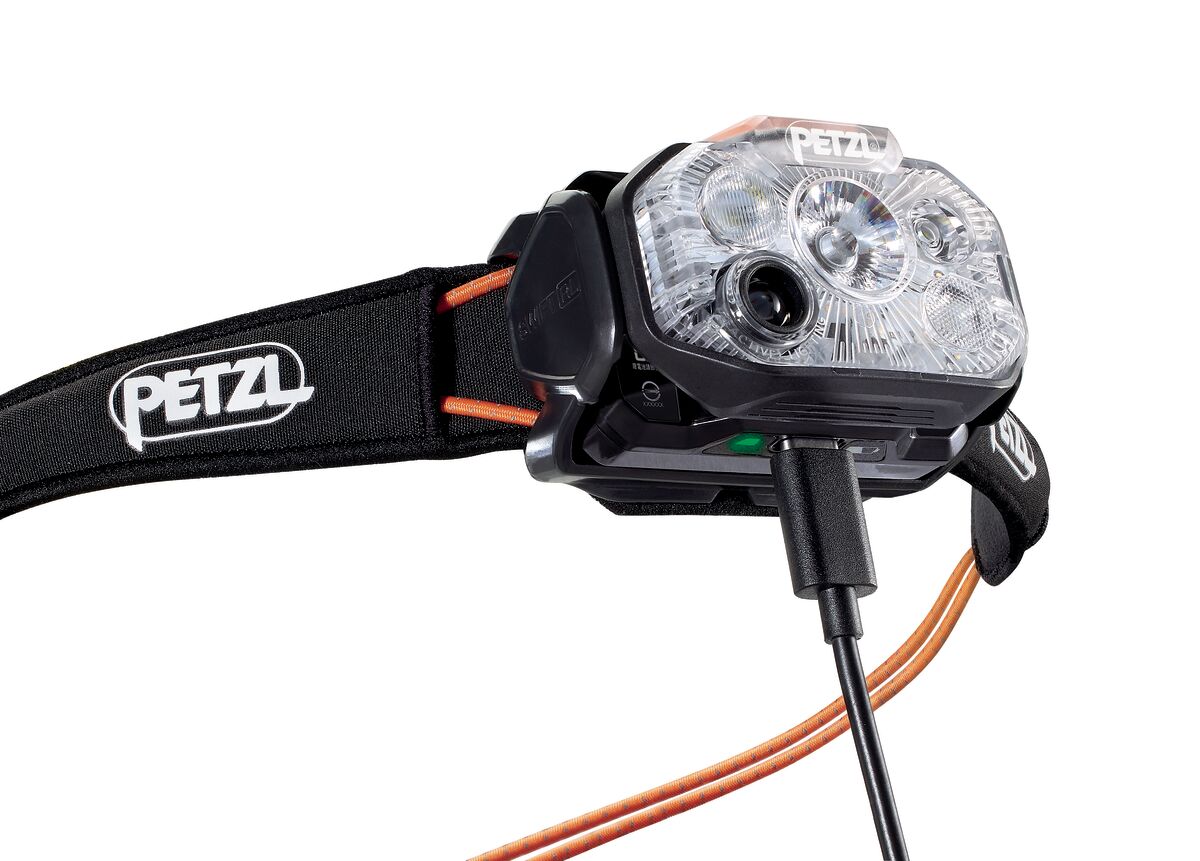 Close-up of the Petzl Swift RL Headlamp charging through a cable plugged into the lamp body