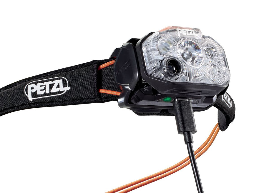 Close-up of the Petzl Swift RL Headlamp charging through a cable plugged into the lamp body