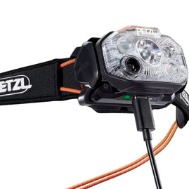 Close-up of the Petzl Swift RL Headlamp charging through a cable plugged into the lamp body