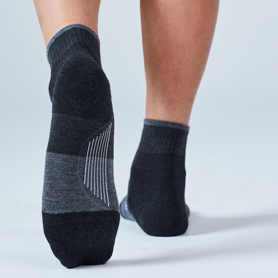 Runner walking away in Feetures Trail Max Cushion Quarter Socks in Charcoal, showing the cushioned sole