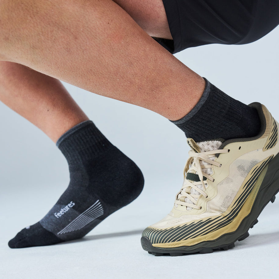 Runner lunging in Feetures Trail Max Cushion Quarter Socks in Charcoal with a trail shoe