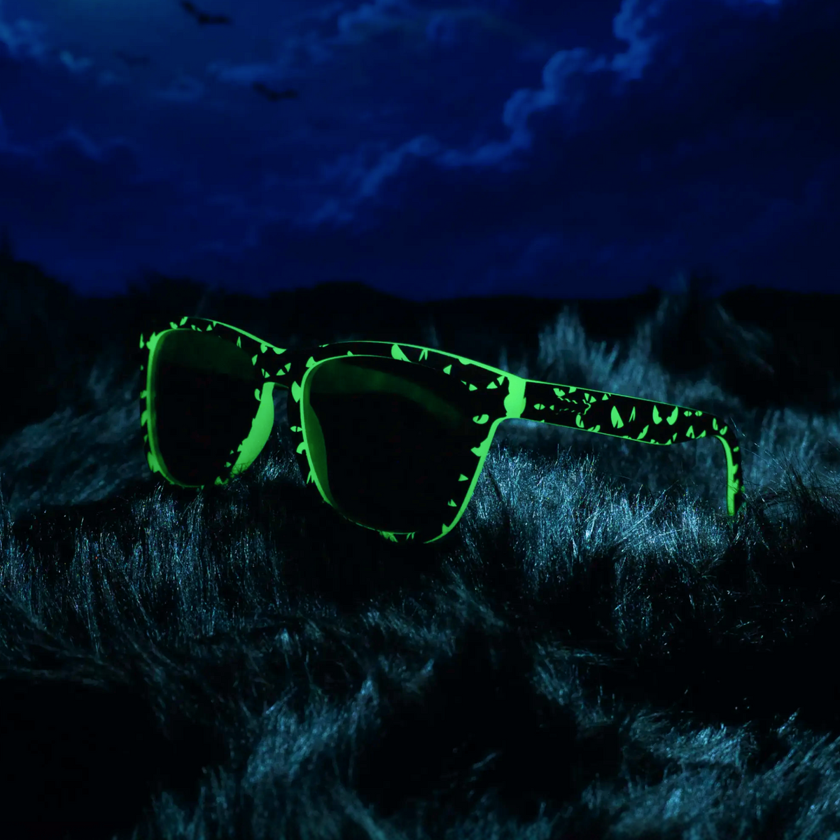 Goodr What Lurks In The Shadows sunglasses glowing green on dark fur under a night sky