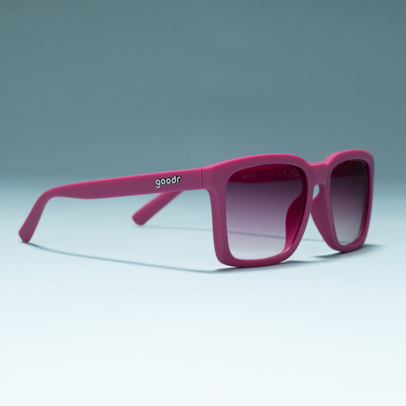 Goodr Living Highlight Reel magenta sunglasses standing open on a pale blue surface