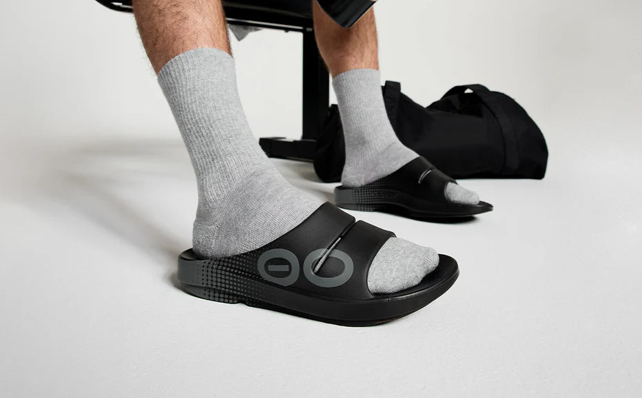OOahh Sport - Unisex by Oofos in black with bold hand-painted strap, OOfoam cushioning for comfort, ideal for post-running recovery