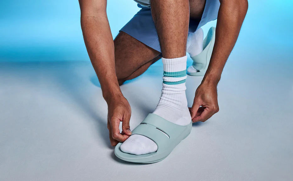 OOahh - Unisex by Oofos in light blue, lightweight slides with OOfoam strap for impact absorption and all-day comfort