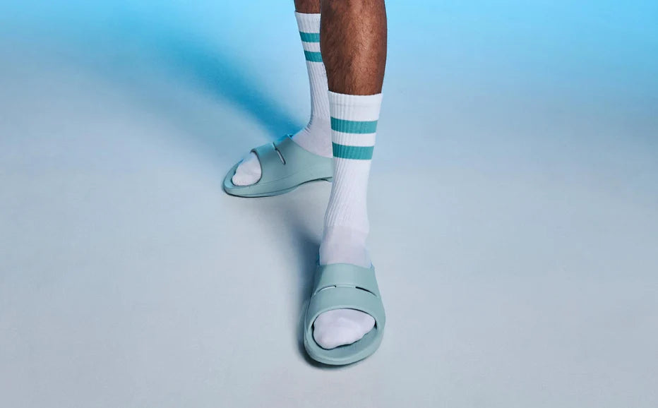 OOahh - Unisex by Oofos in light blue with OOfoam strap for extra support, impact absorption, and comfort for casual wear and recovery