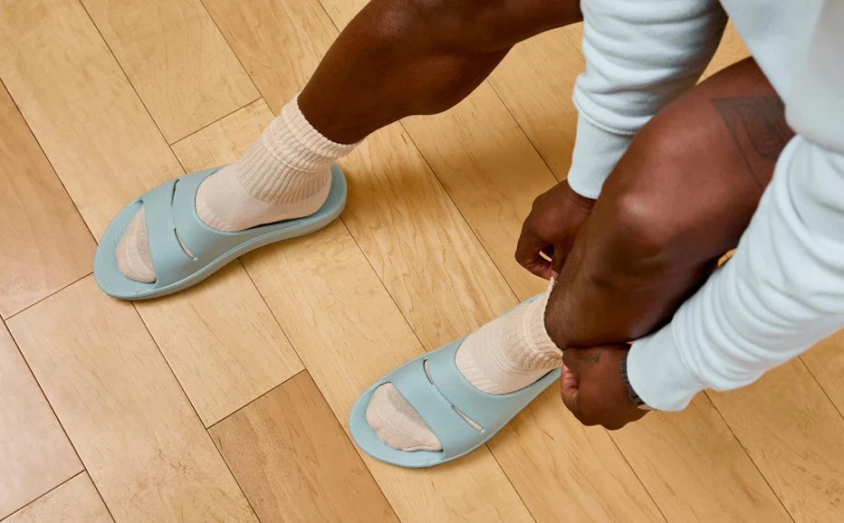 OOahh - Unisex by Oofos in light blue and beige with OOfoam strap cushioning for impact absorption and all-day comfort slides
