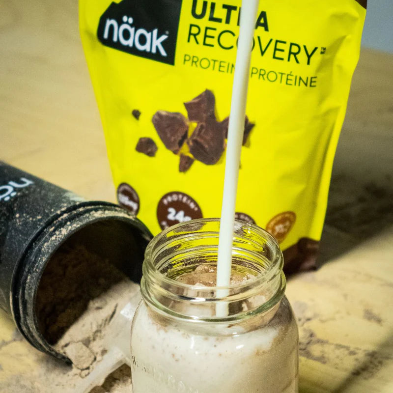 Protein Powder Chocolate by Naak in yellow packaging with chocolate pieces, high-protein powder for muscle recovery and rehydration