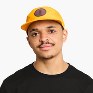 Man in a black t-shirt wearing the orange-yellow Ciele GOCap Comp Ninety in Solis, front view