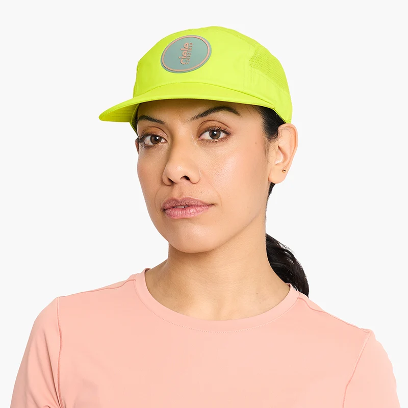 Woman in a pink t-shirt wearing the neon yellow Ciele GOCap Comp Ninety in Gekko, front view