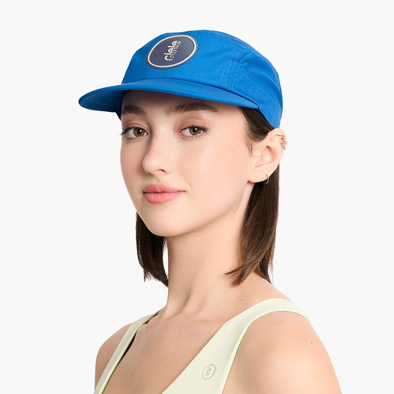 Woman wearing the Ciele GOCap Comp Ninety in Azure, three-quarter view showing the round patch