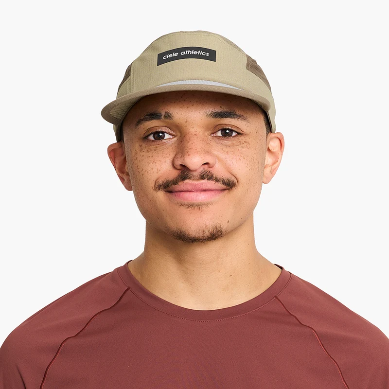 Man in a red shirt wearing the Ciele GOCap - Field - IconicBar in Cub, front view