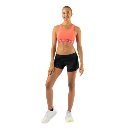 Full-length view of a woman in a coral Rabbit Utili Bra-Vo with pink patterned band and black shorts